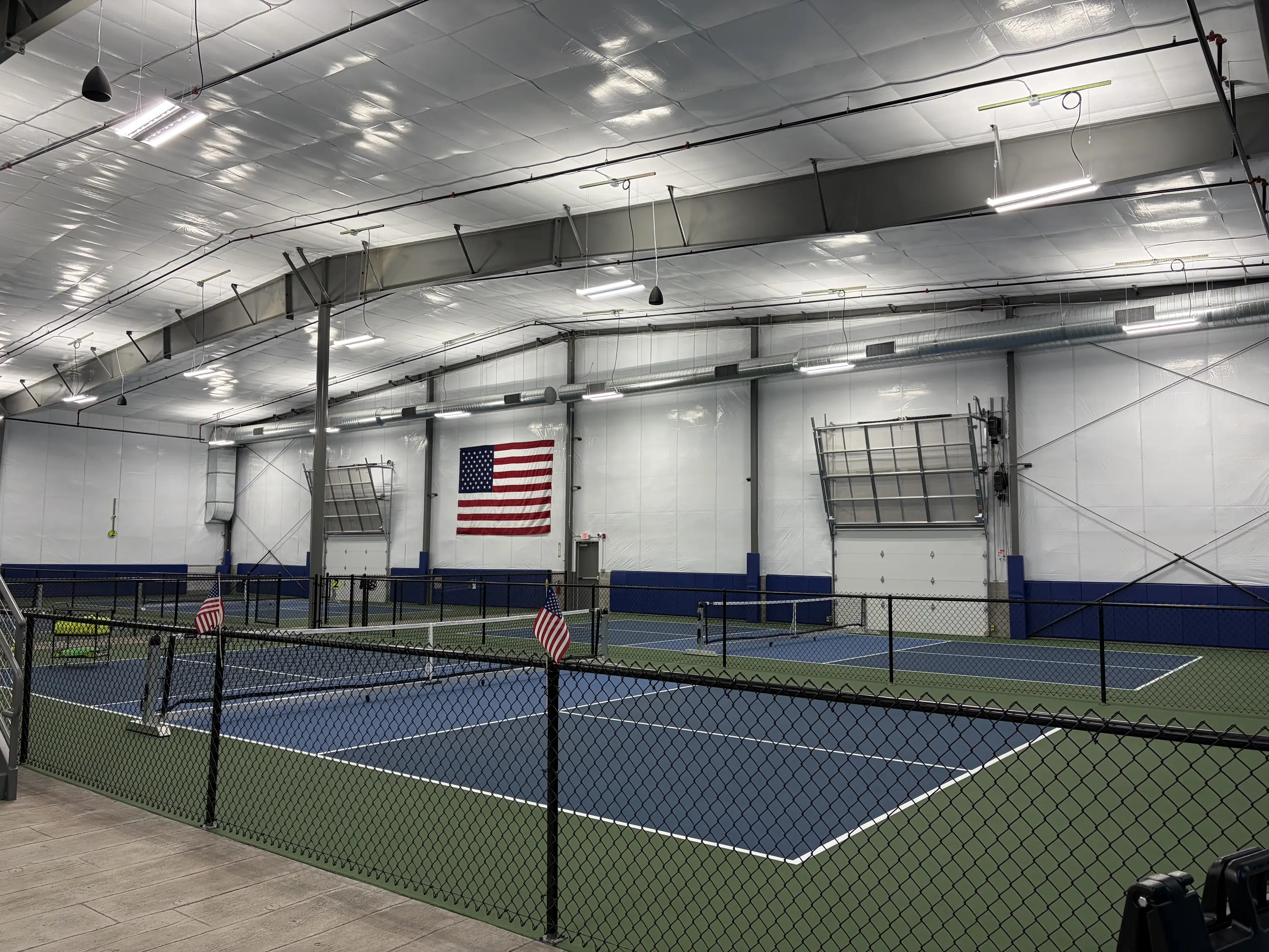 Wide view of indoor pickleball courts with American flag on the wall